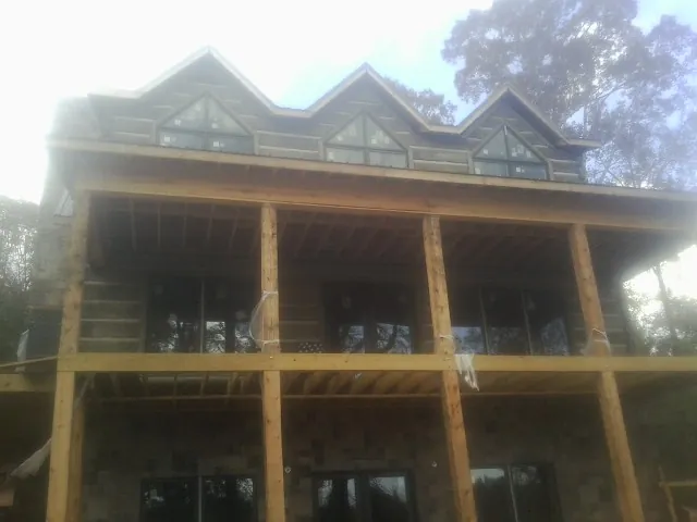 Dormers and porch framing on a large log home under construction — Roof Coating work by our crew in Metairie
